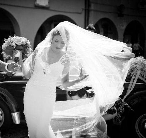 la sposa mentre scende dall'auto aiutata dalla wedding planner